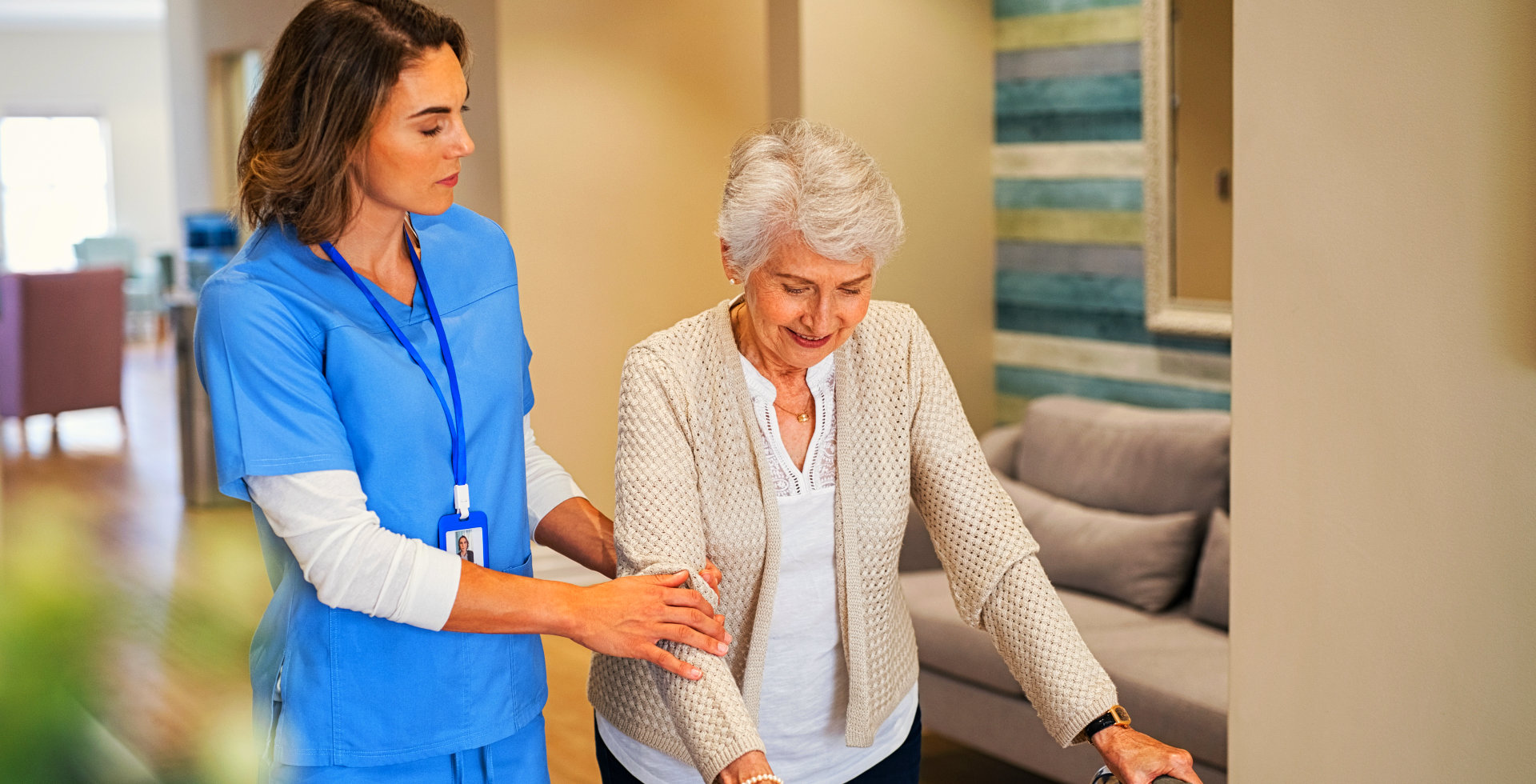 carer assisting elderly woman to walk