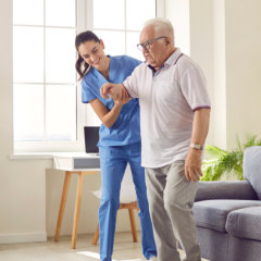 caregiver helping senior man to walk